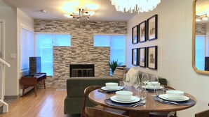 A dining area with a round wooden table set for four, a stone wall, and a fireplace. - Walnut Mews - Quiet Creekside townhome next to Pearl Street (Boulder)