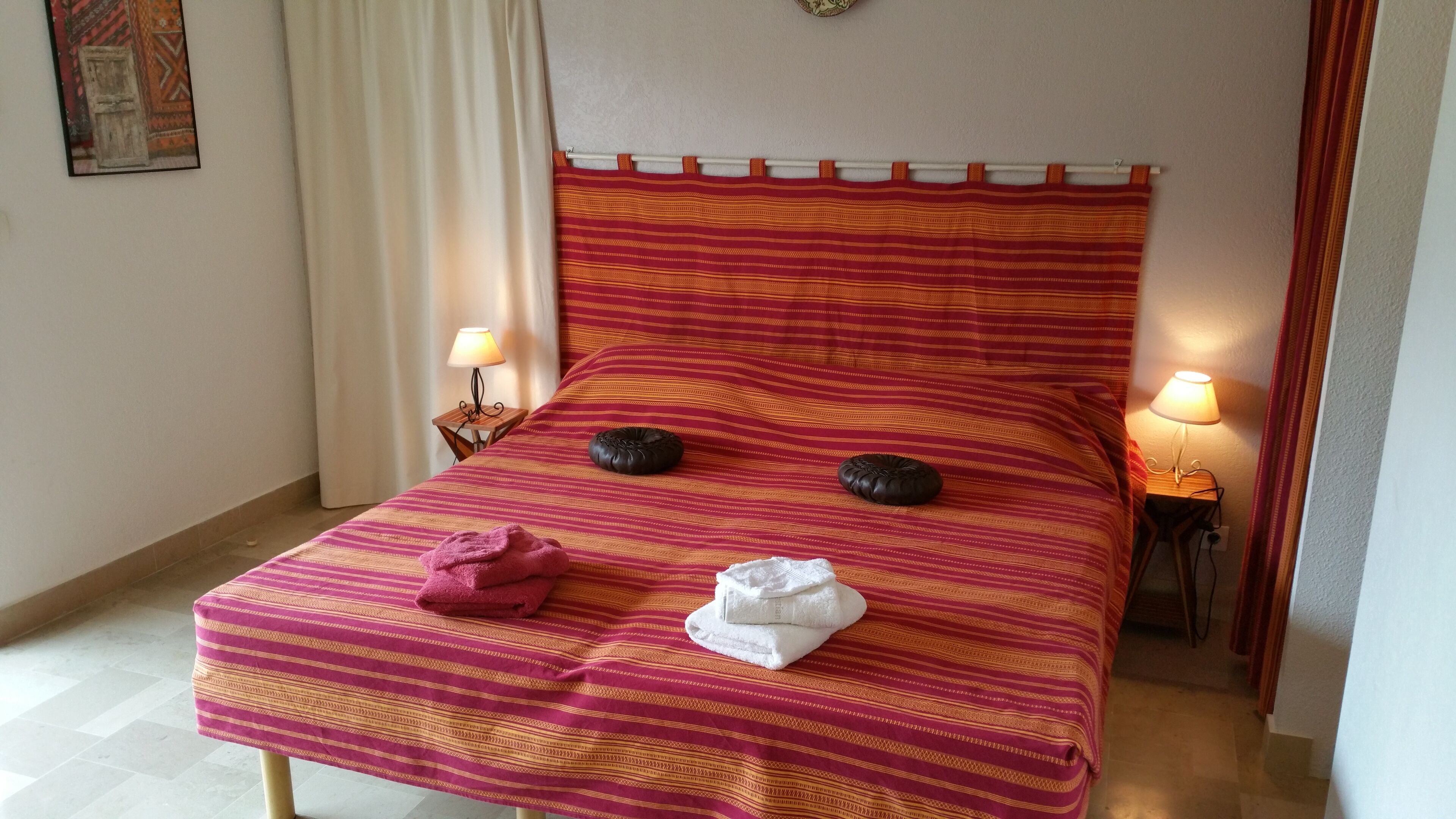 A bed with a striped bedspread, two pillows, and two folded towels.