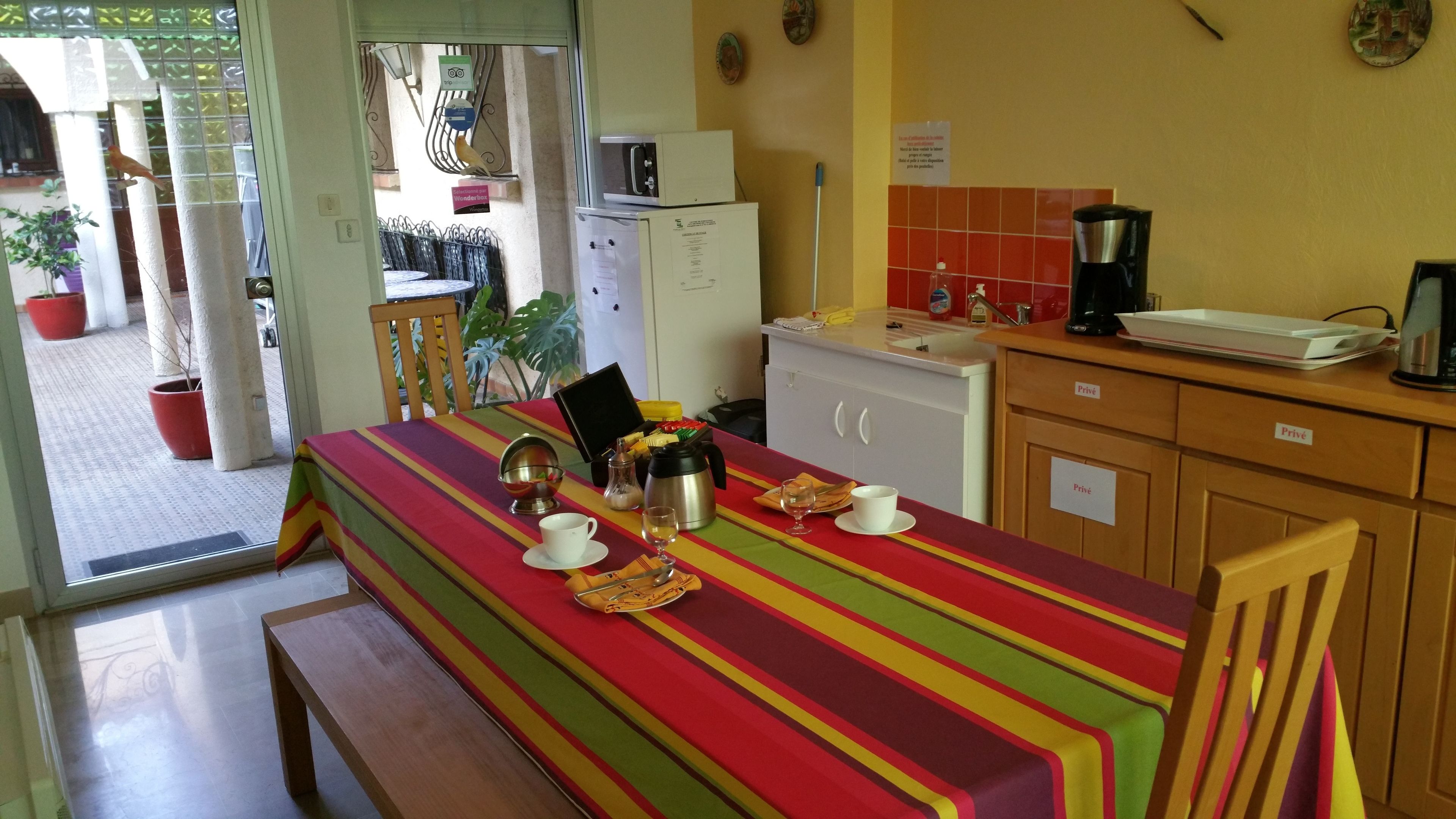 A dining area with a striped tablecloth, a coffee maker, and a microwave.