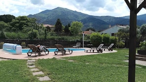 A backyard with a swimming pool, lounge chairs, and a view of mountains. - Al Pati (Sorede)