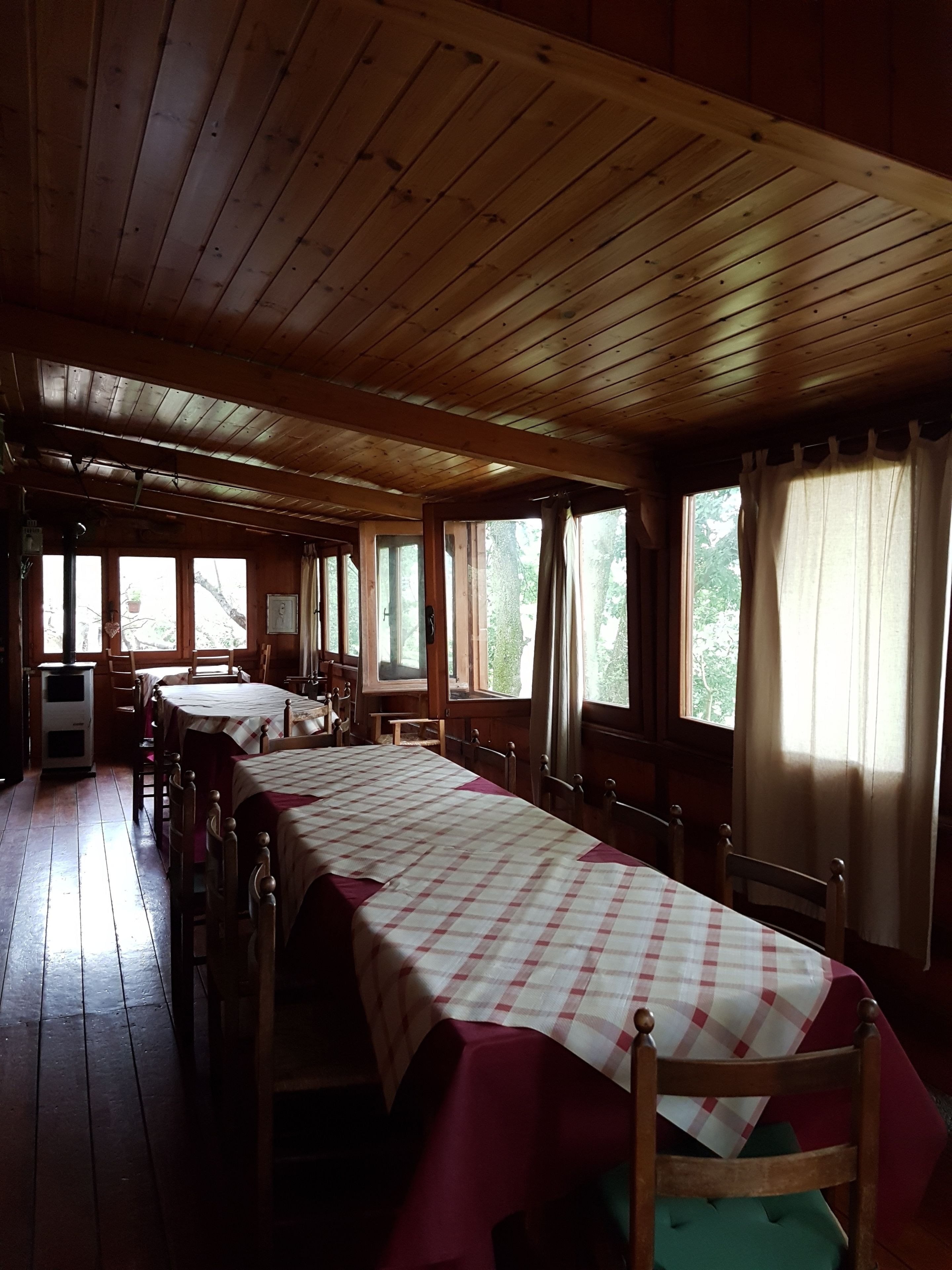 Een kamer in chaletstijl met een lange eettafel, houten vloeren en grote ramen.