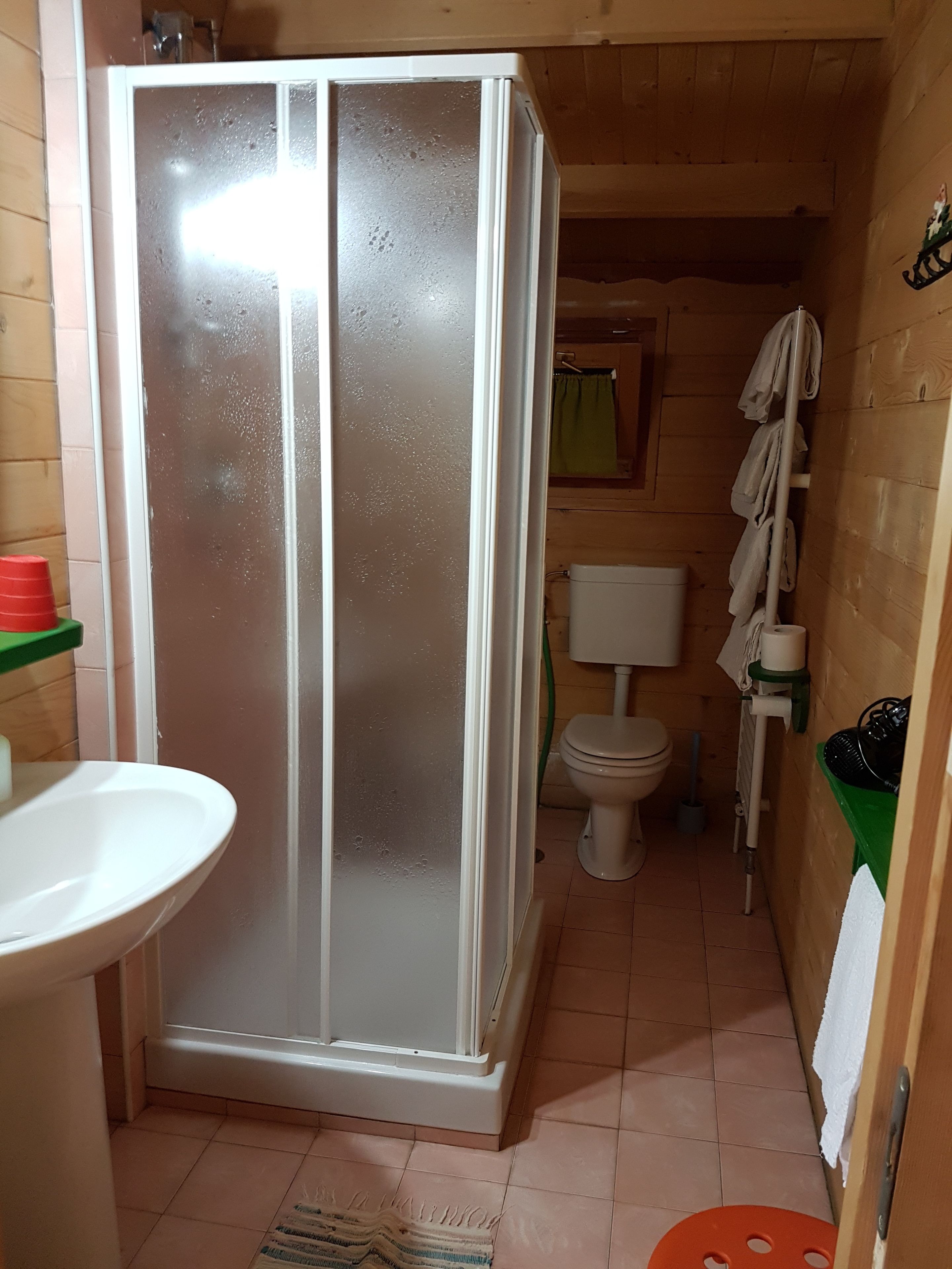 Une petite salle de bain compacte, dotée d’une cabine de douche, de toilettes et d’un lavabo.