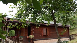 A rustic cabin with a wooden exterior, a porch with a bench, and a brick foundation. - Agriturismo Cisogna (Anagni)