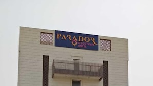 A hotel named "Parador Boutique Hotel" with a modern design, featuring a large sign and a well-maintained garden with various plants. - Hotel Parador (Firozabad)