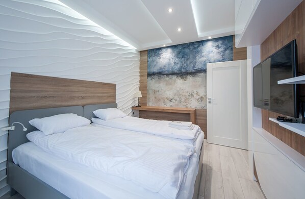 A modern bedroom with a large bed, bedside tables, a TV, and a unique textured wall.