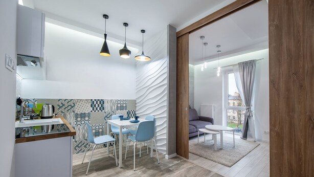 A modern kitchen with a dining area, featuring a kitchen island, a dining table with chairs, and pendant lighting.