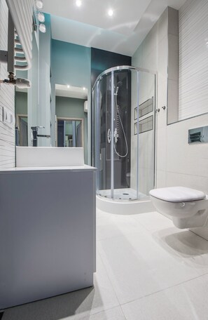 A modern bathroom with a glass-enclosed shower, a white bathtub, and a toilet.