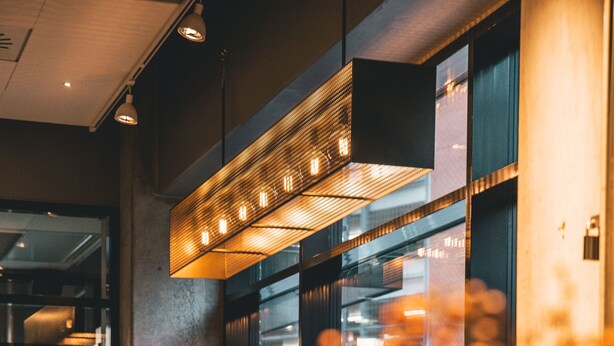 A modern bar area with a long counter, bar stools, and a decorative hanging light fixture. - Four Points Flex by Sheraton Aalborg (Aalborg)