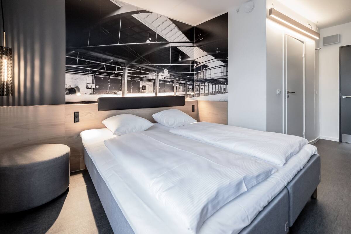 Une chambre d’hôtel moderne dotée d’un grand lit, d’un coin salon et offrant une vue sur l’intérieur de l’hôtel.