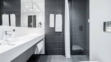 A modern bathroom with a large mirror, white sink, and a shower area.