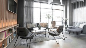 A modern living room with a sofa, armchairs, a coffee table, and a bookshelf. - Four Points Flex by Sheraton Aalborg (Aalborg)