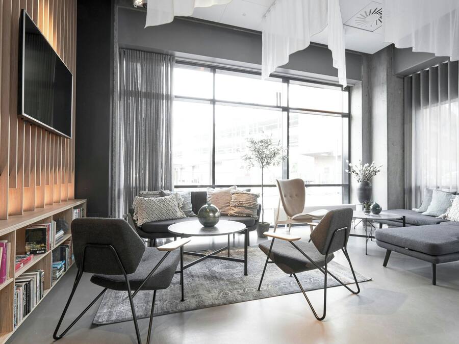 A modern living room with a sofa, armchairs, a coffee table, and a bookshelf.