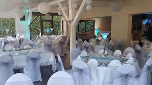 A banquet hall with round tables, white tablecloths, and chairs with white sashes. - Domaine des Pierres Dorées (Ternand)