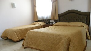 A hotel room with two beds, a wooden headboard, a nightstand, and a window with curtains. - Akdeniz Hotel (Mersin)