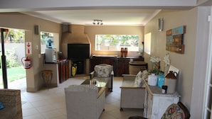 A spacious living area with a kitchen, a fire extinguisher, and a window overlooking a garden. - Four Seasons Guesthouses (Lephalale)