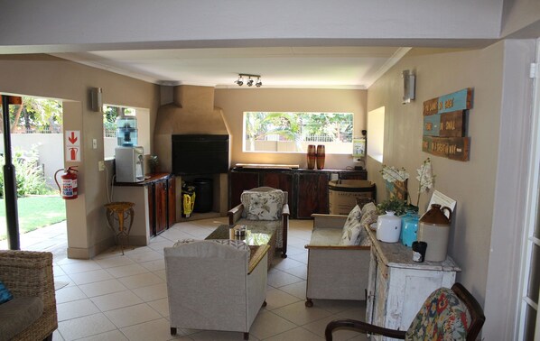 A spacious living area with a kitchen, a fire extinguisher, and a window overlooking a garden.