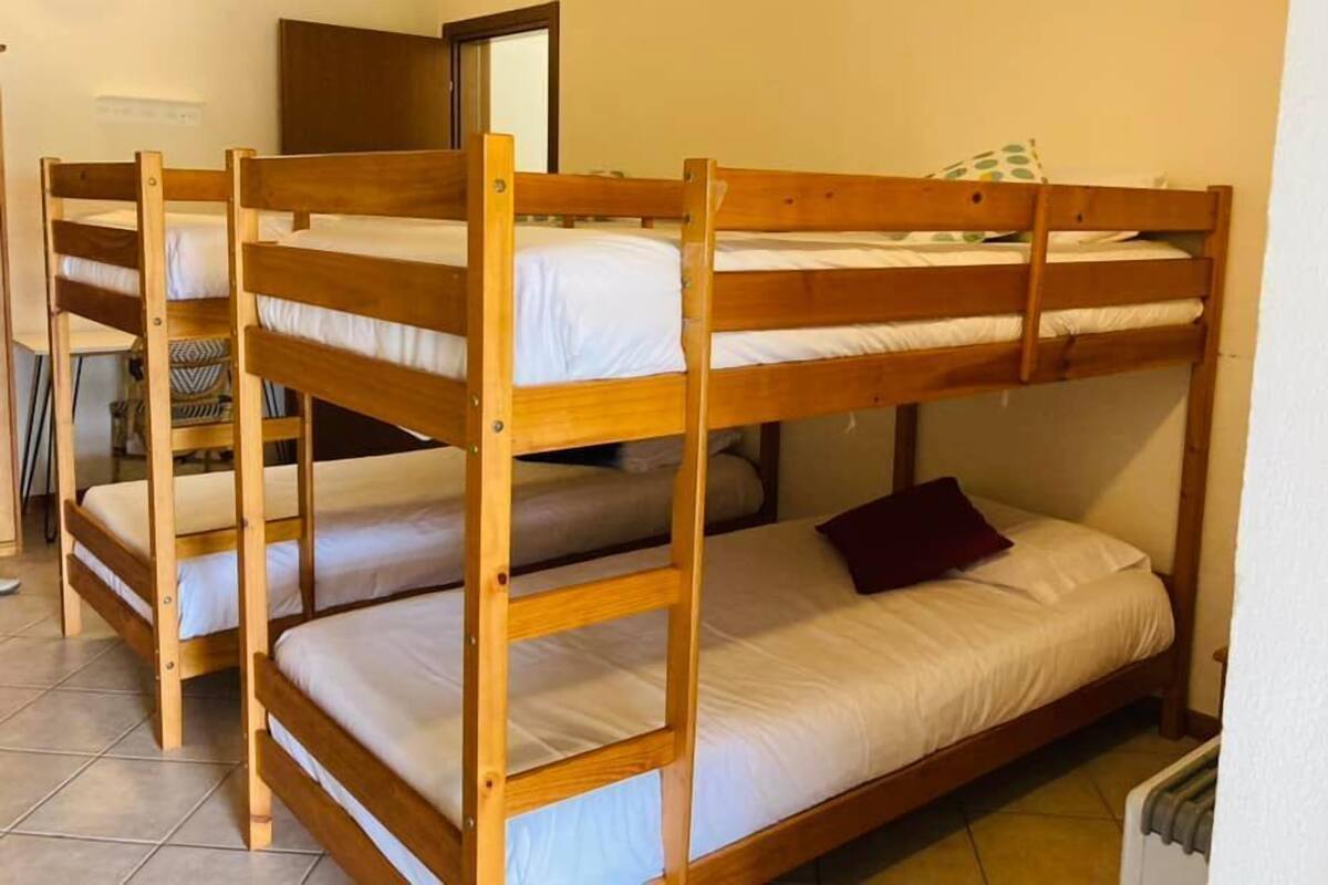 A room with three bunk beds, a mirror, and a radiator.