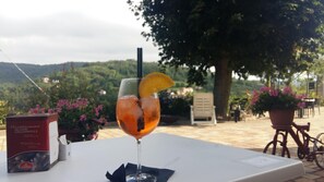 Ein Tisch mit einem Getränk, einer Schachtel und Blick auf einen Garten und Hügel.