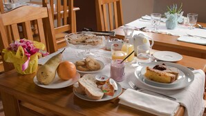 Una mesa de desayuno con pan, fruta y bollería.