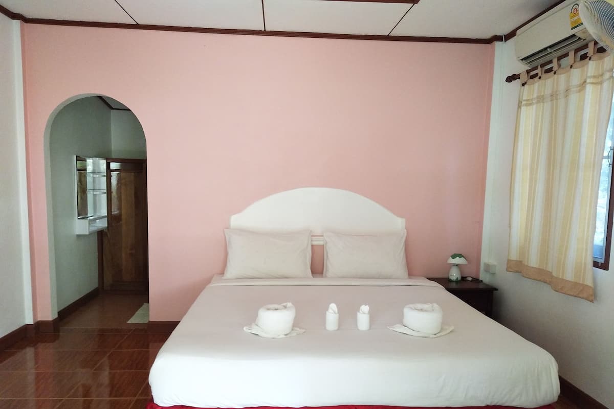 Une chambre d’hôtel avec un lit, une table de chevet, un miroir et une fenêtre avec des rideaux.