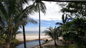 Vista de la playa con palmeras y una terraza de madera.