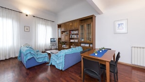 A cozy living room with a sofa, a television, a wooden cabinet with books, and a dining table with chairs. - Proconsolo (Florence)