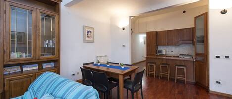 Un espacio habitable compacto con comedor, cocina y estantería.