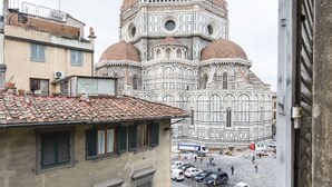 A view of the Florence Cathedral with its distinctive dome and intricate facade, seen from a building's window overlooking a street with parked cars and pedestrians. - Proconsolo (Florence)