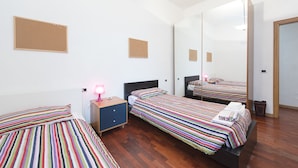 A hotel room with two beds, a nightstand, a mirror, and a corkboard on the wall. - Proconsolo (Florence)