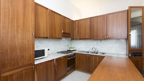 A kitchen with wooden cabinets, a microwave, a gas stove, and a sink. - Proconsolo (Florence)