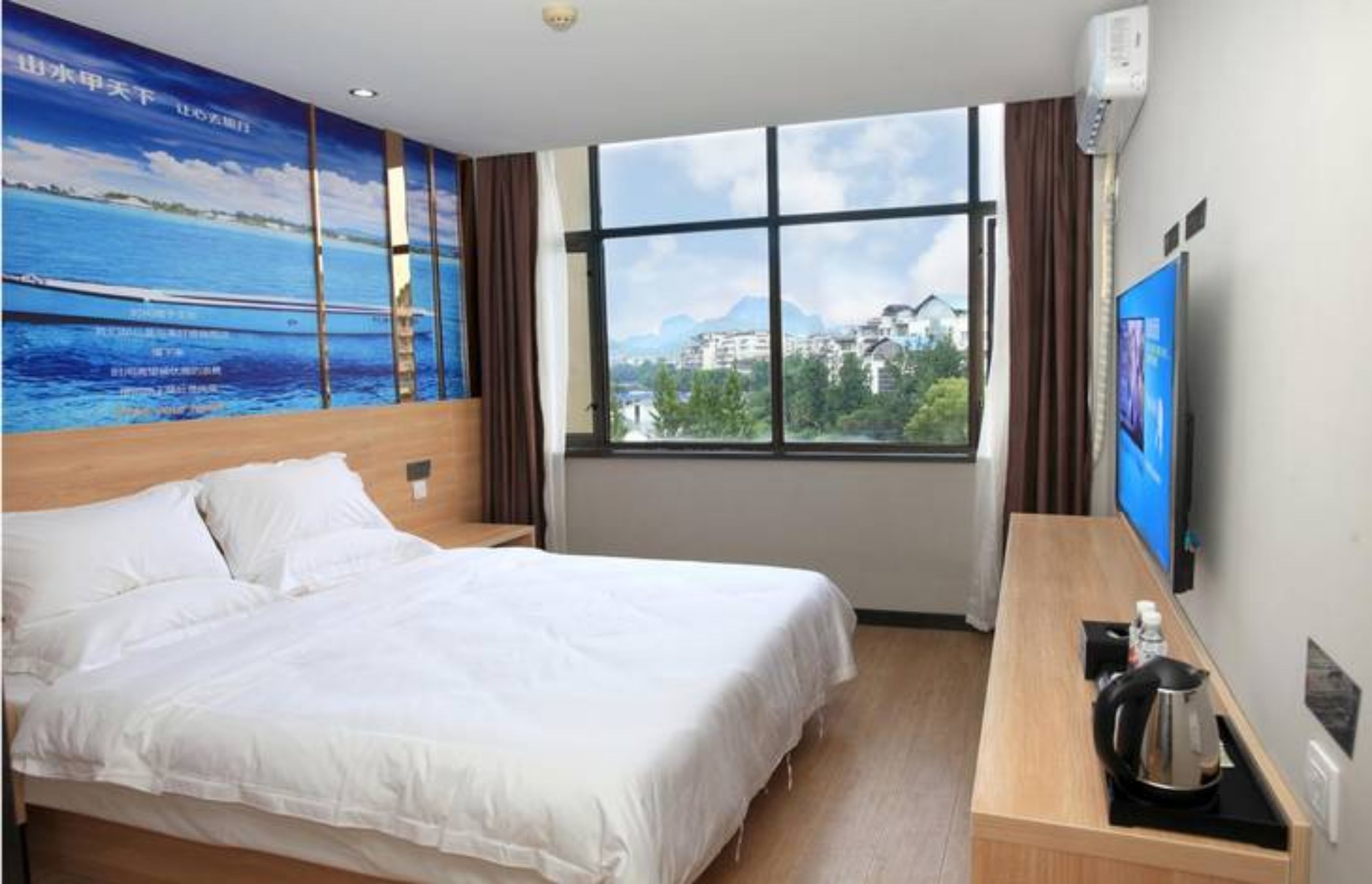 Une chambre d’hôtel avec un grand lit, une table de chevet en bois, une télévision et une fenêtre donnant sur la ville.