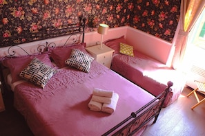 A bedroom with a bed, pillows, a nightstand, and a lamp. - Rumariya Rooms Hostel (Rome)