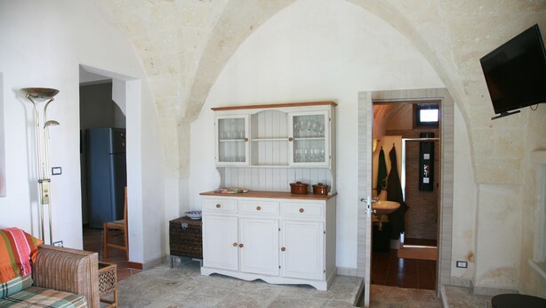 A room with a white cabinet, a television mounted on the wall, and a doorway leading to a bathroom.
