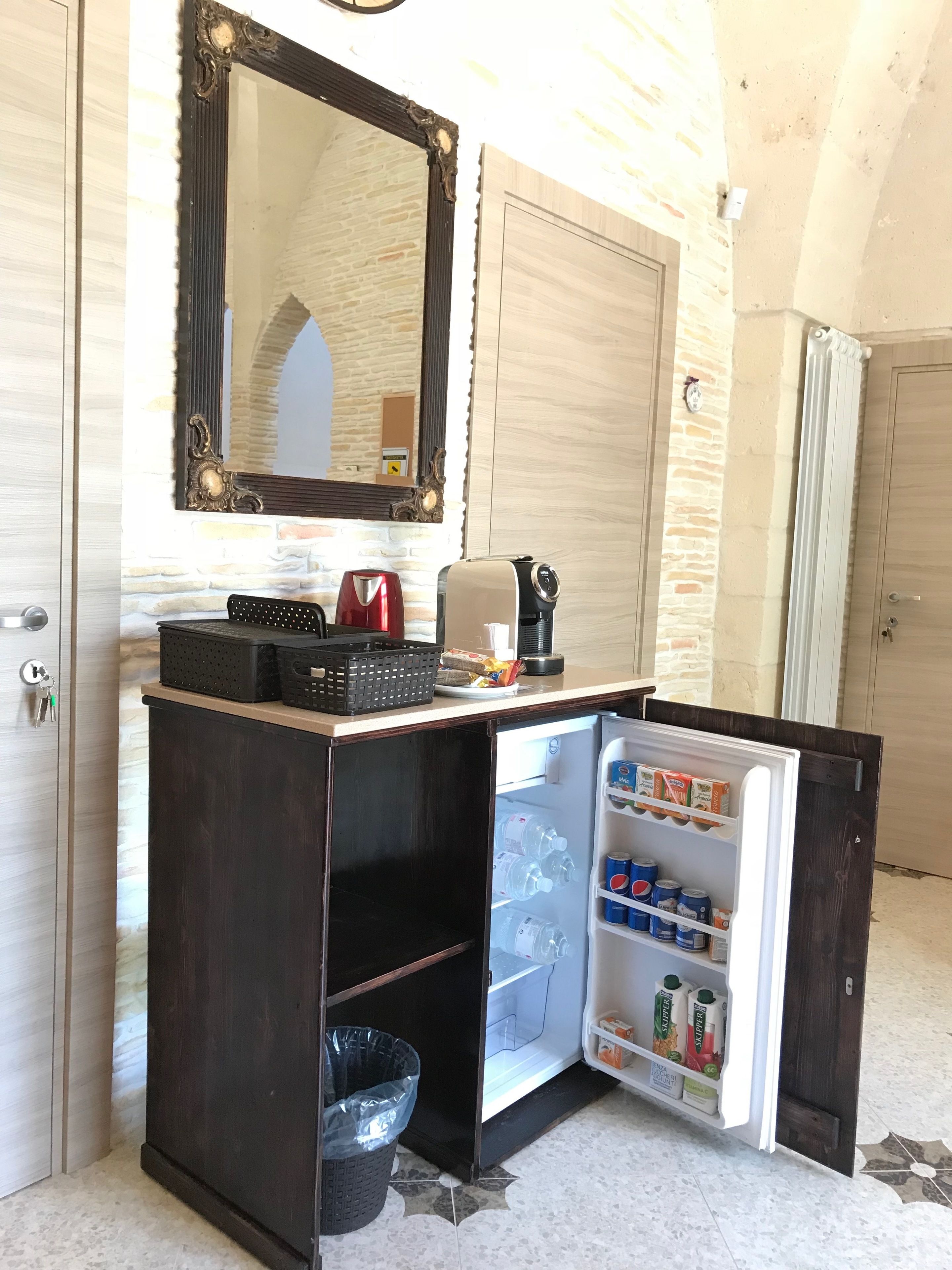 A compact minibar with a refrigerator, a coffee maker, and a kettle.