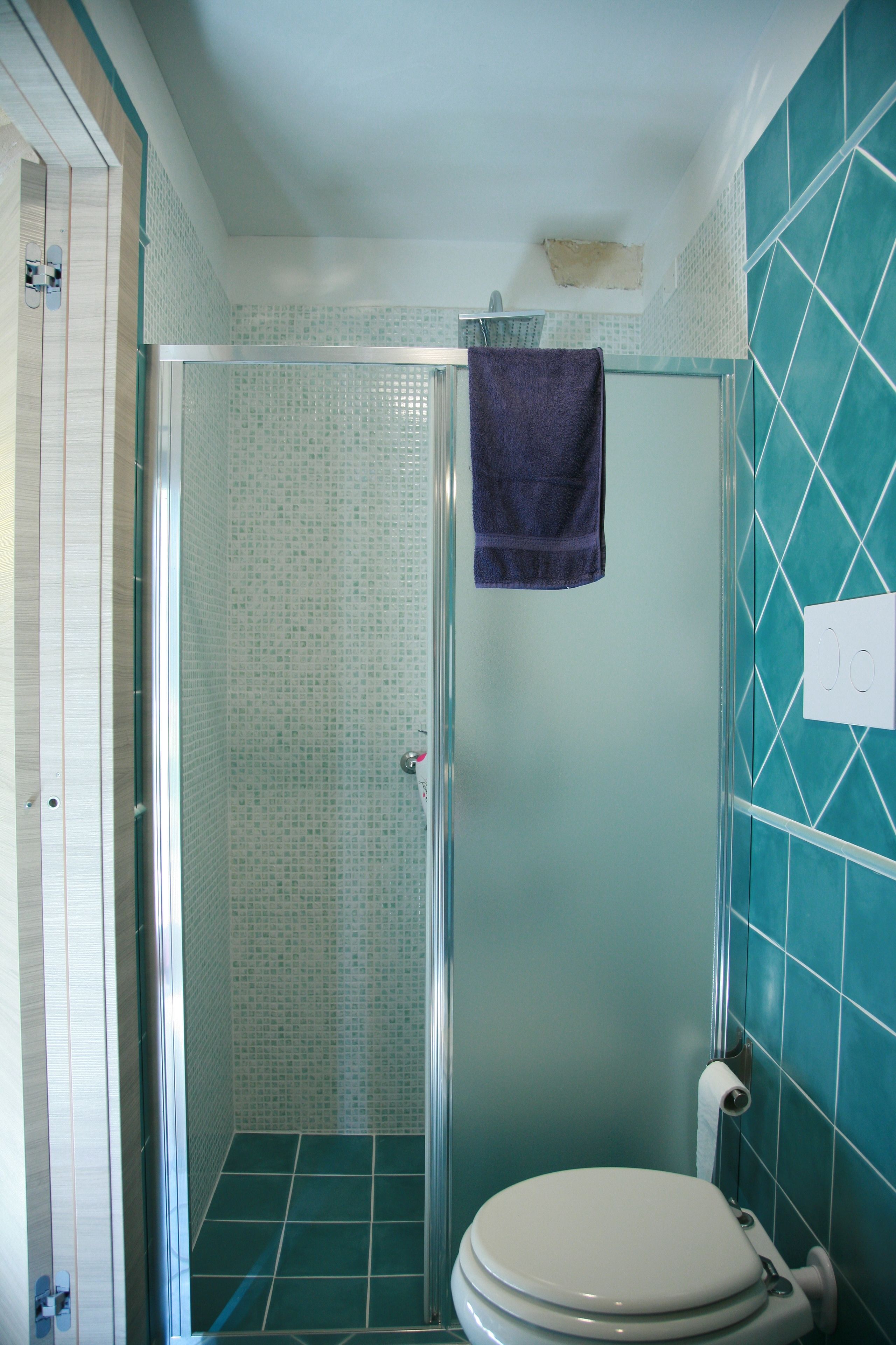 Ein Badezimmer mit Duschkabine, Toilette und Wand mit geometrischem Fliesendesign.
