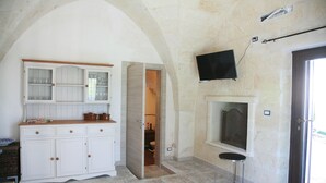 A room with a white cabinet, a television mounted on the wall, and a door leading to another room.