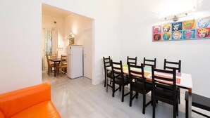 A dining area with a table and chairs, a refrigerator, and a colorful artwork on the wall. - Repubblica (Florence)