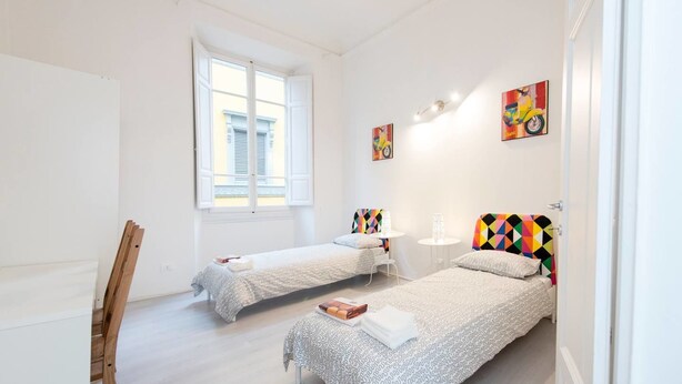A modern bedroom with two single beds, a desk, and a window. - Repubblica (Florence)