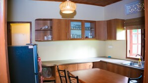 Une cuisine compacte avec des meubles en bois, un réfrigérateur, une table à manger avec des chaises et une fenêtre donnant sur un beau paysage.