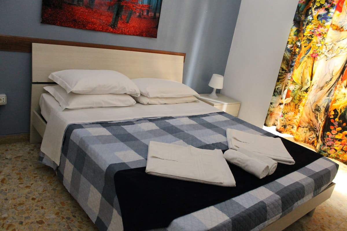 Un lit bien fait, avec une couverture à carreaux, des coussins joliment disposés et des serviettes pliées posées sur le lit.