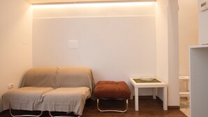 A small, well-lit room with a bed, a stool, and a small table with a bowl. - Elisa Apartment (Florence)