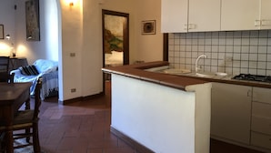 Cuina compacta amb salabost a la paret, un rentamànega i una cuina. Hi ha una zona de menjador amb taula i cadires.