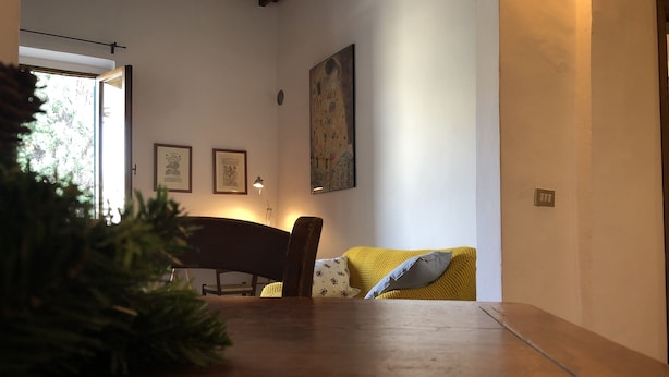 Un saló tranquil amb una taula de fusta, un sofà groc i un piano.