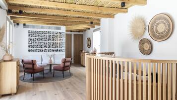 Un interior moderno con techo de madera, una mesa redonda con sillas, un mostrador de recepción de madera y decoración en las paredes.