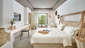 A modern bedroom with a bed, bedside table, and a view of the outdoors. - Adorno Beach Hotel & Suites (Mykonos)