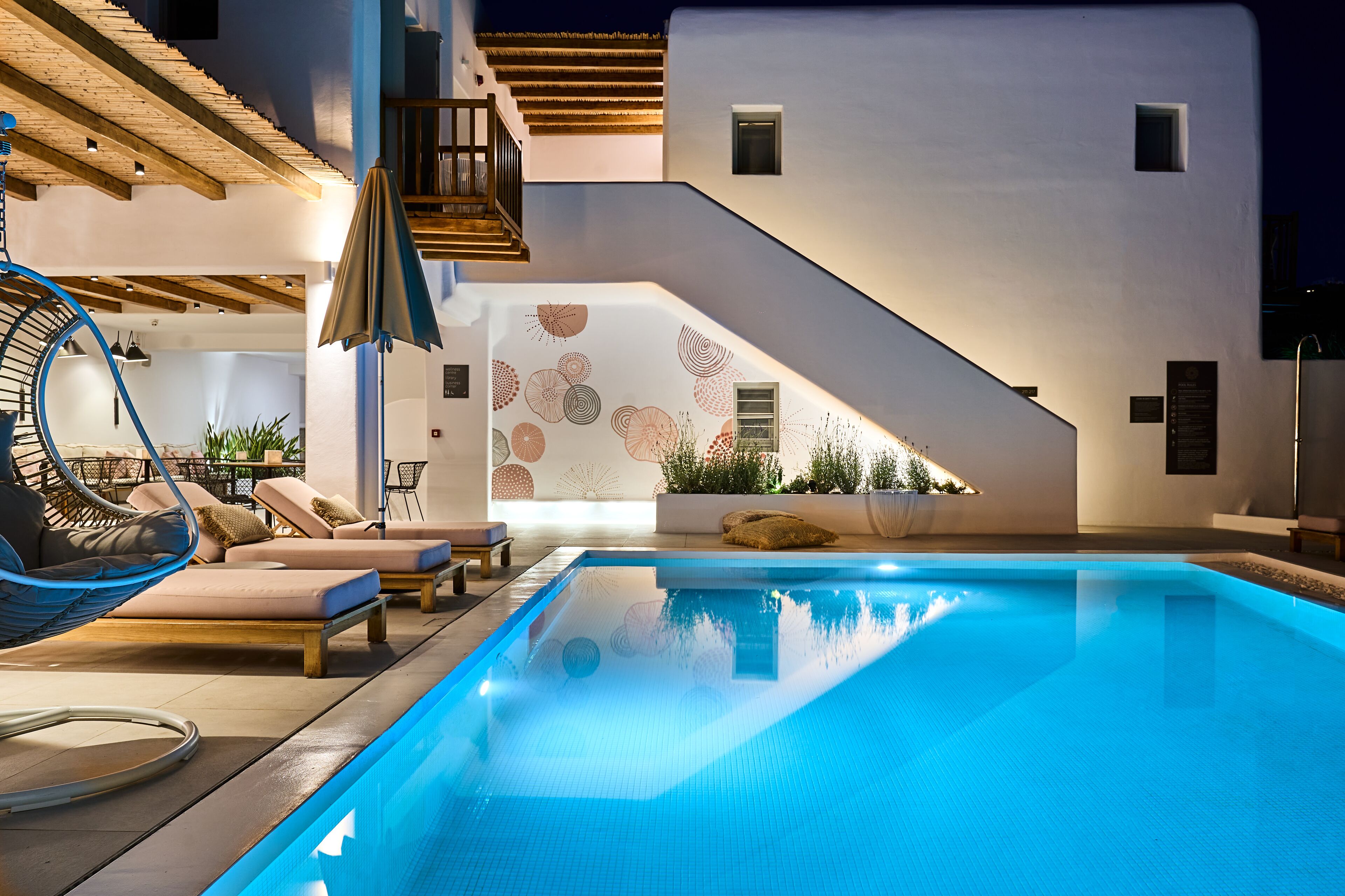 A modern pool area with a clear blue pool, wooden deck, and lounge chairs.