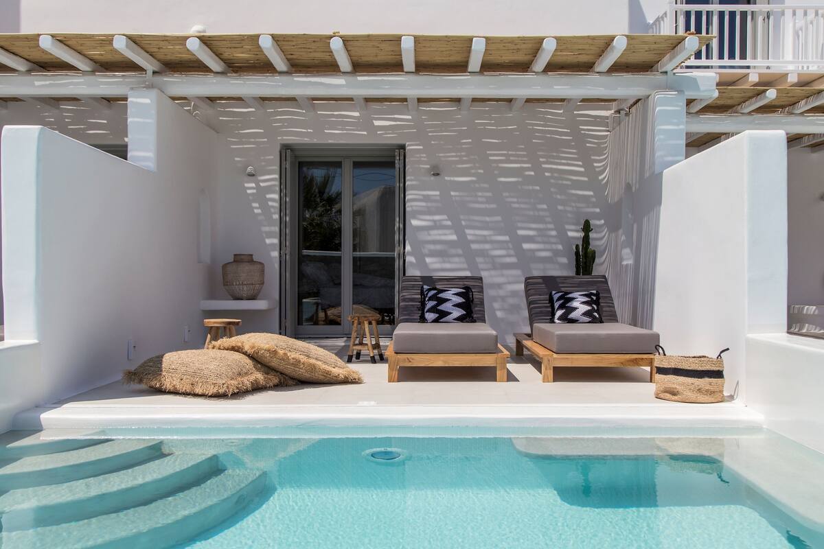 Zona de piscina con dos sillones de relax, un taburete y una cesta de mimbre.