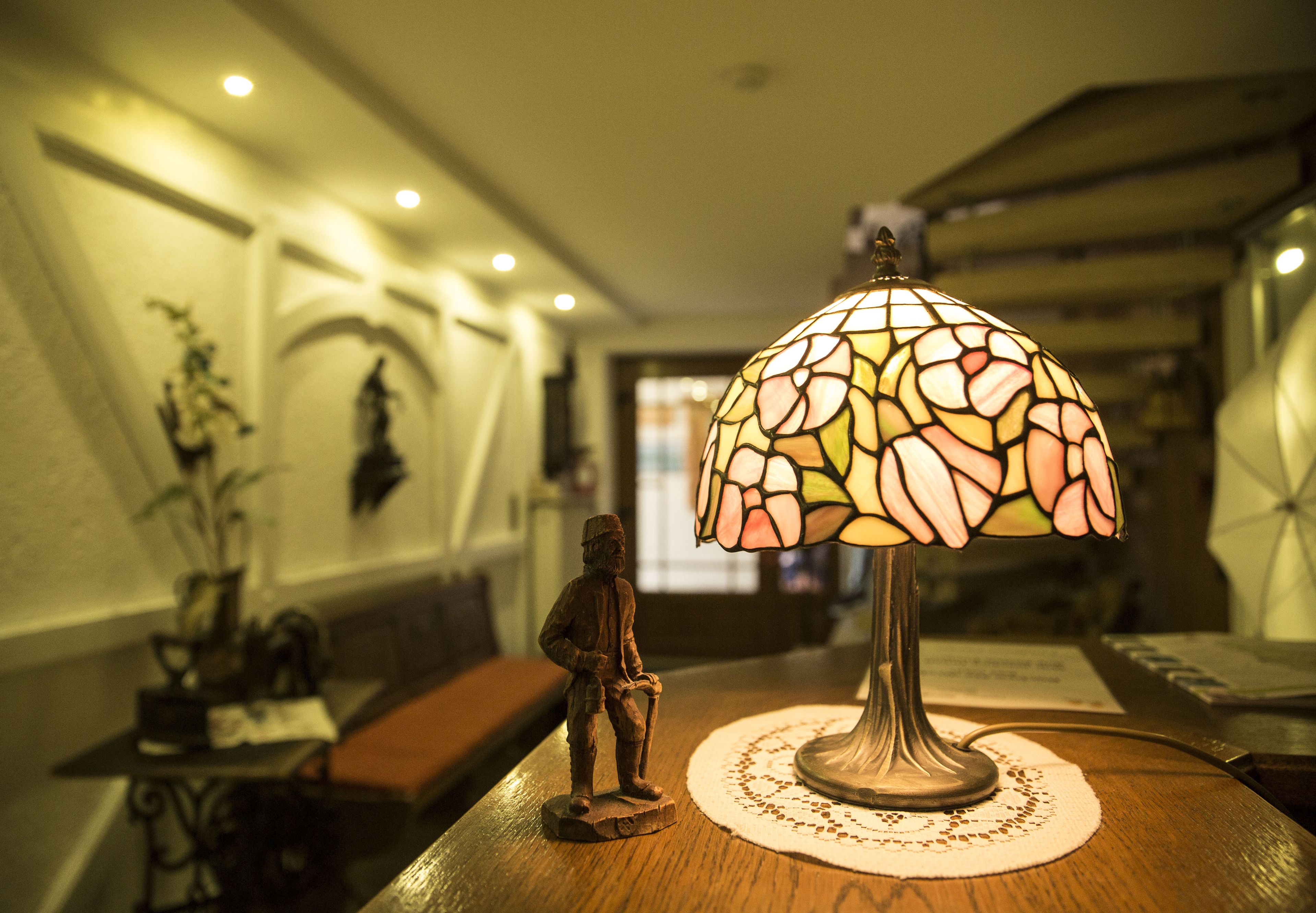 A table with a stained glass lamp, a small figurine, and a doily.