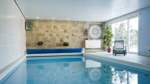 A swimming pool with a tiled wall featuring various patterns and a bench. - Landhaus Fischer (Braunlage)