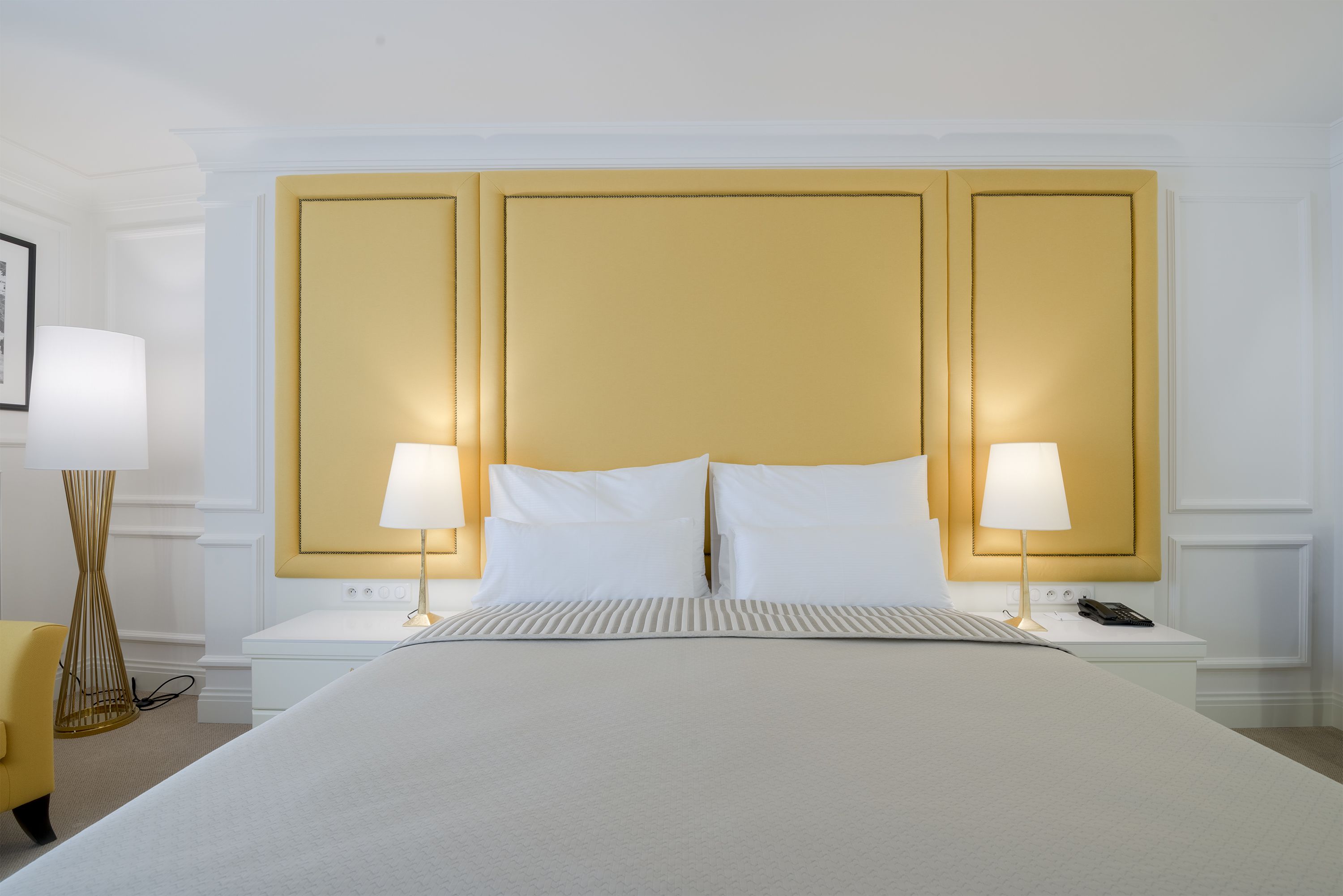 A hotel room with a large bed, two bedside tables, a lamp on each table, and a chair.